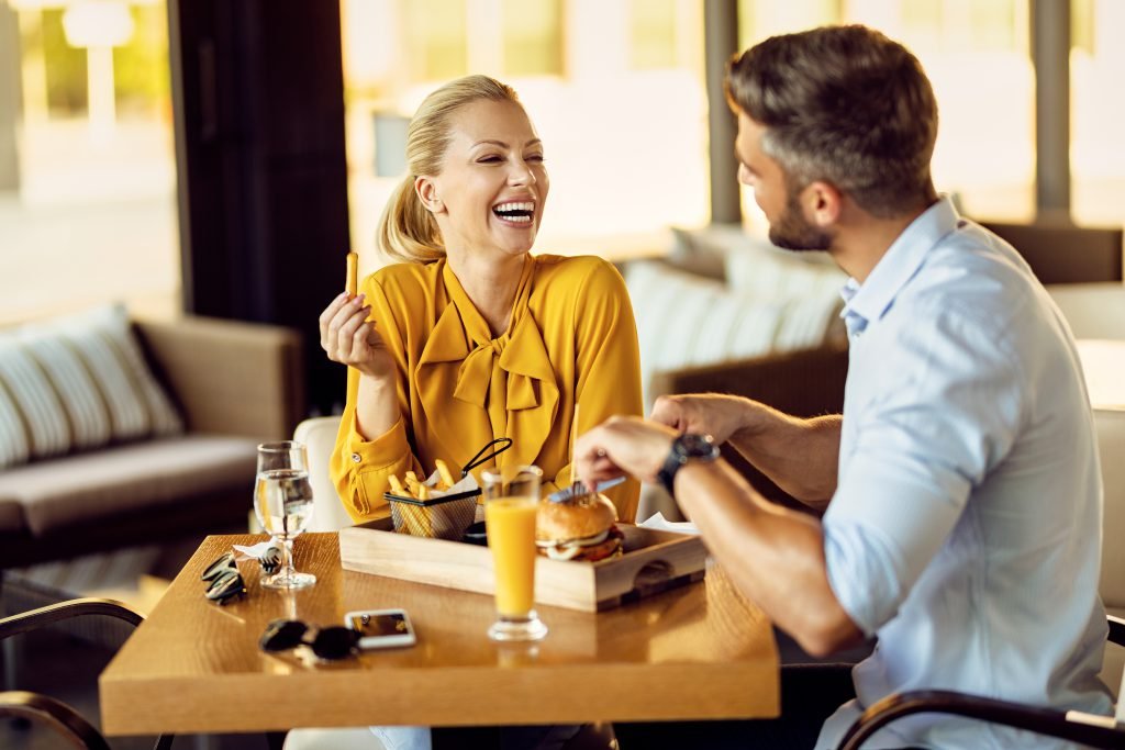 Happy woman having fun while talking to her boyfriend during a lunch in a restaurant.