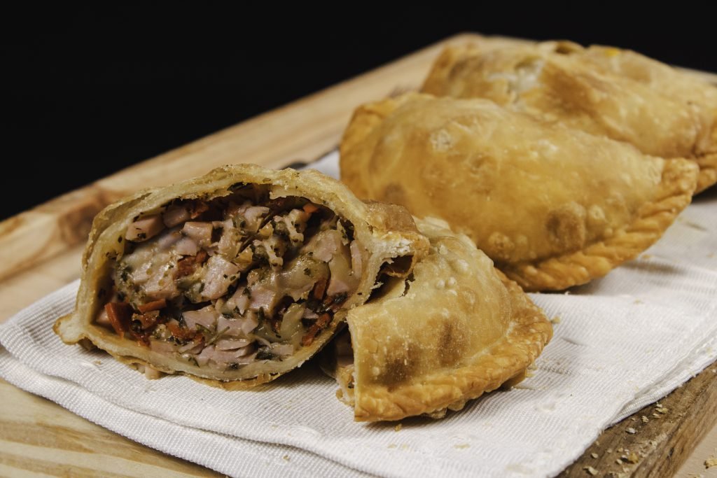 A Neapolitan empanada opened in half, in front of more empanadas.