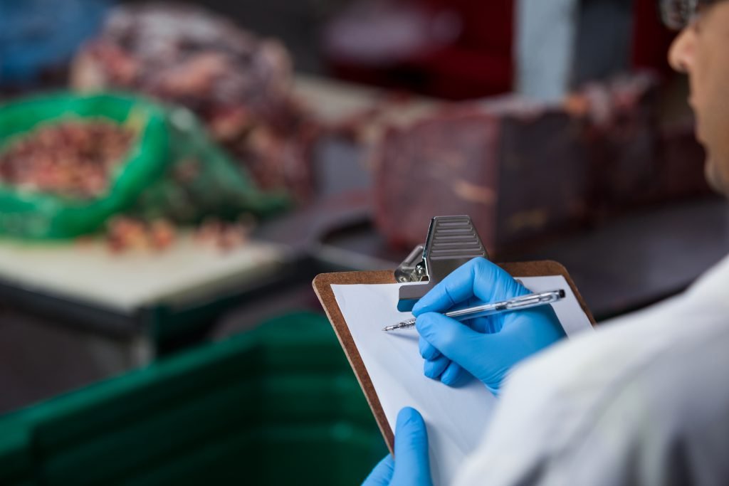 Technicians maintaining records on clipboard at meat factory